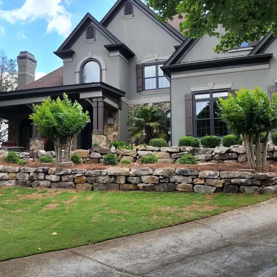 Boulder retaining walls and ornamental trees framing a landscaped home