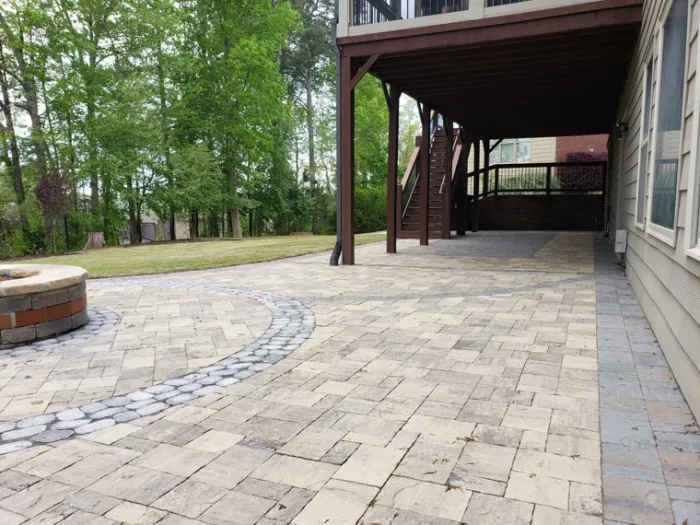 Paver patio and fire pit extending from the house into a wooded yard