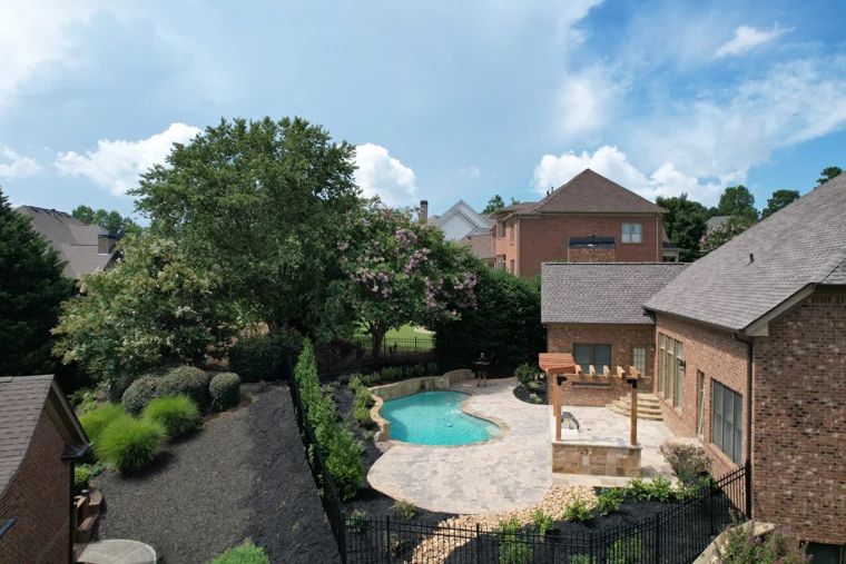 Swimming pool, stone pool deck, and pergola seen from above