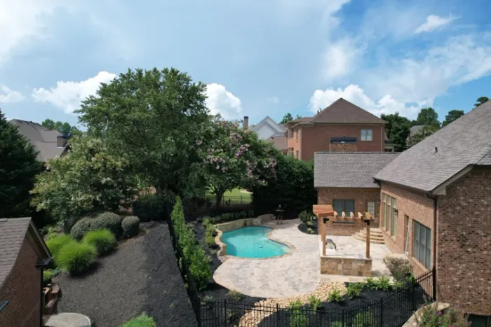 Swimming pool, stone pool deck, and pergola seen from above