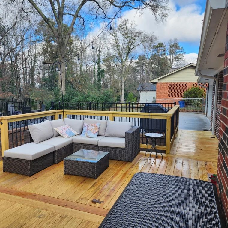 Wood deck furnished with a sectional sofa and black metal railings