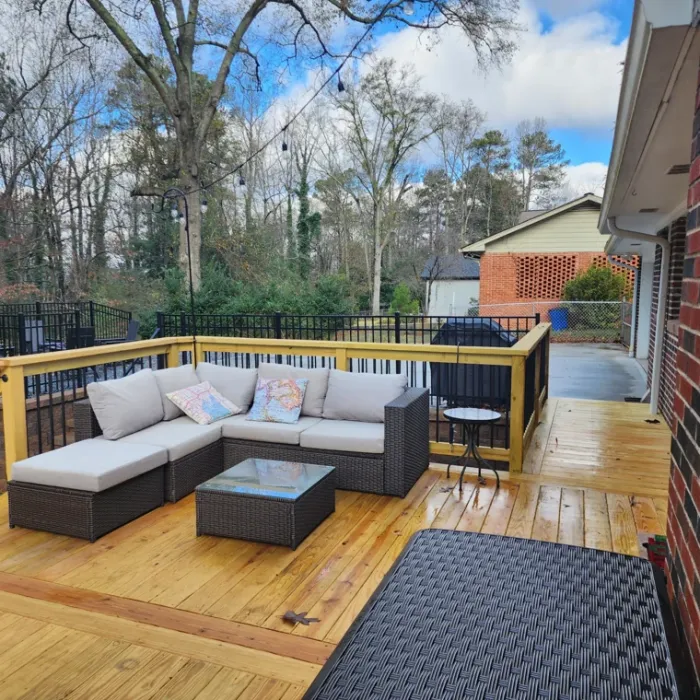 Wood deck furnished with a sectional sofa and black metal railings