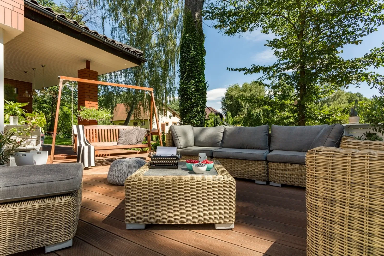 Furnished wood deck with woven lounge seating and mature shade trees