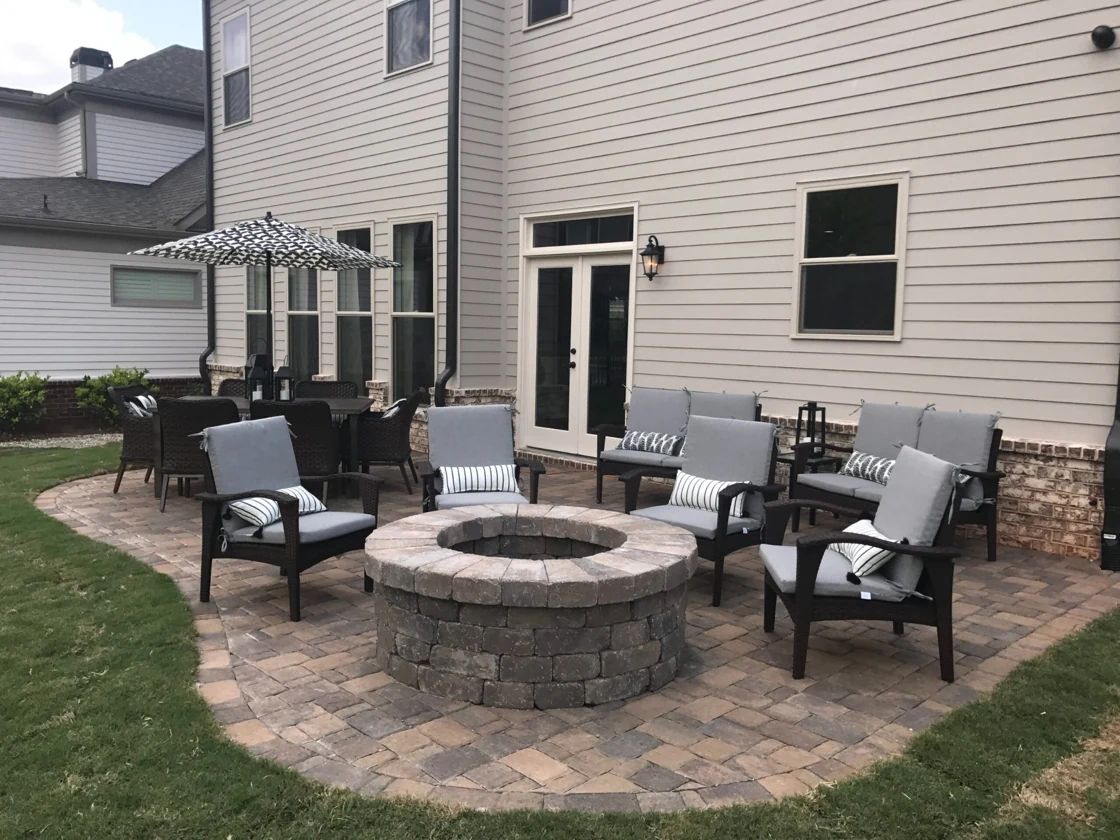 Stone fire pit with lounge chairs beside a backyard dining area