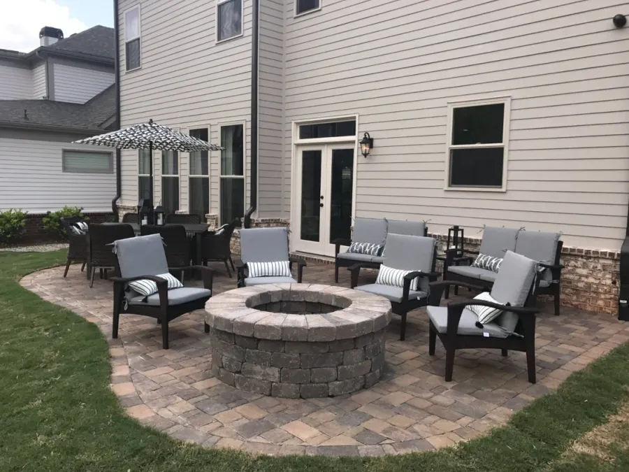 Stone fire pit with lounge chairs beside a backyard dining area