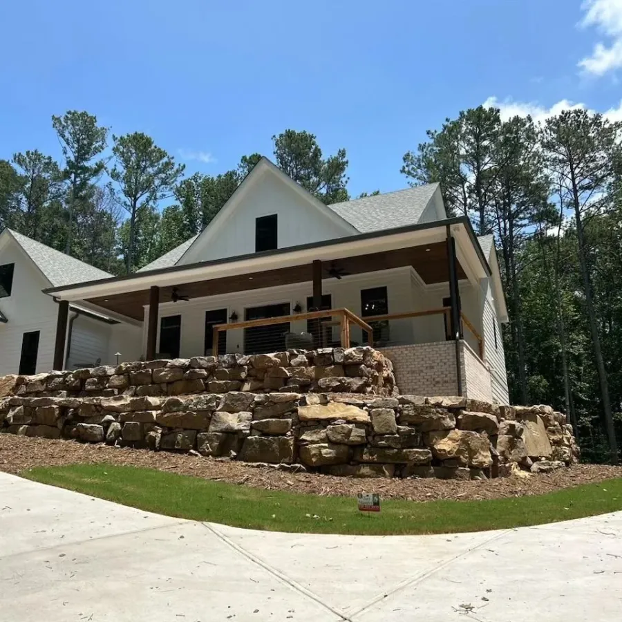 Natural boulder retaining wall and planted terraces in front of a home