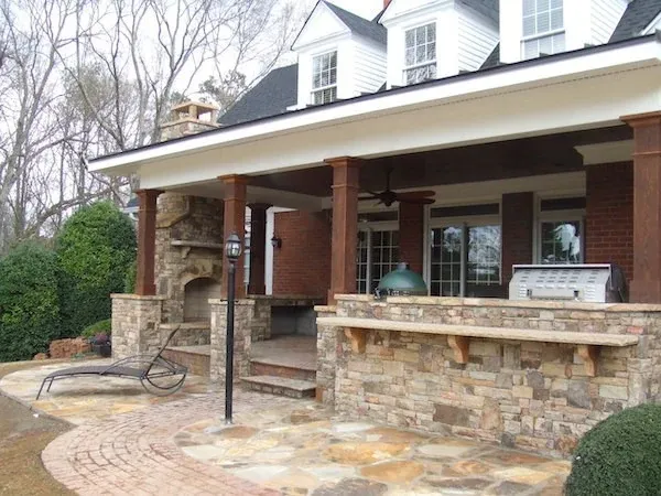Covered stone outdoor kitchen with a grill and counter seating