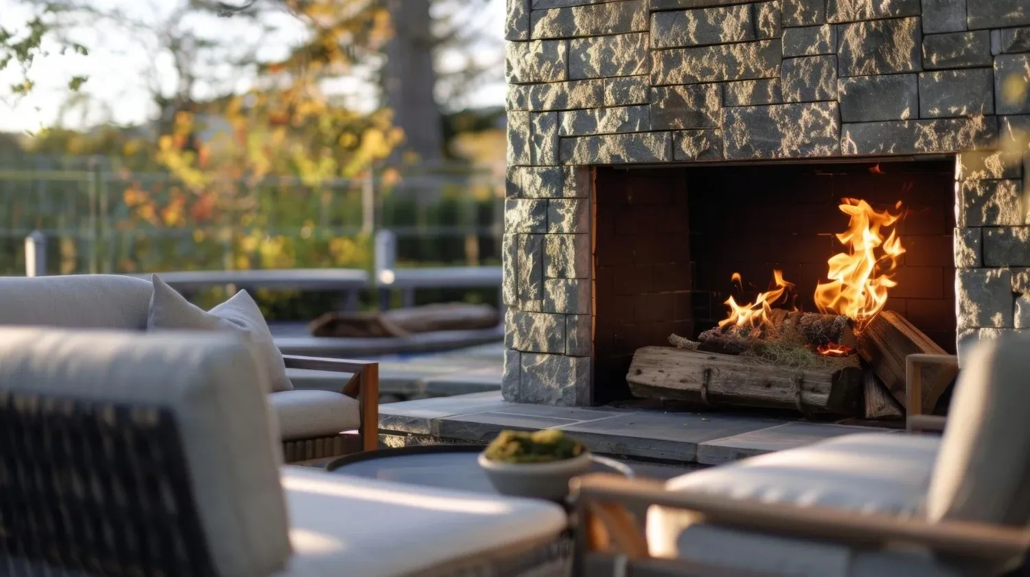 Stone outdoor fireplace with comfortable lounge seating on a landscaped terrace
