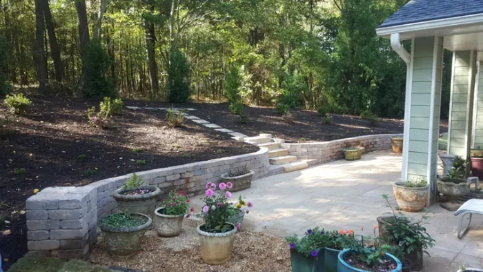 Curved block retaining wall and steps beside a planted backyard patio