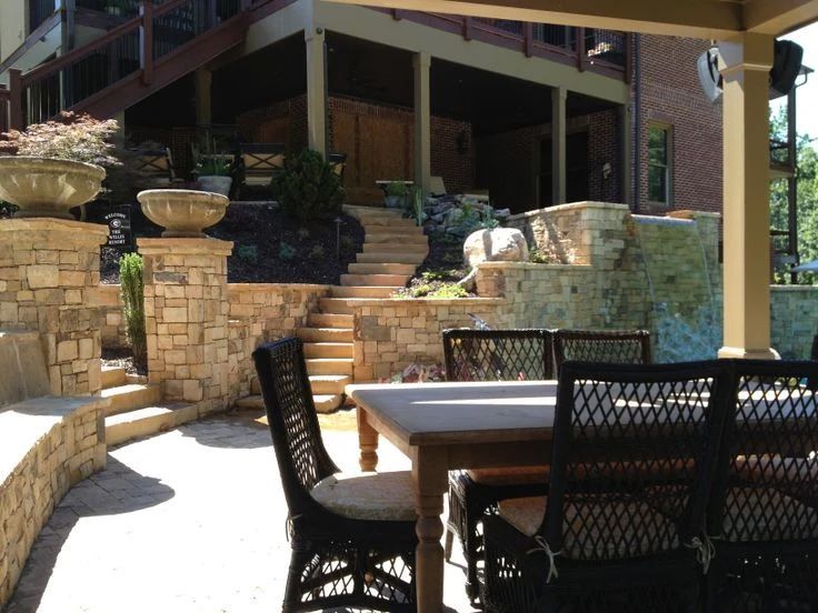 Stone patio and outdoor dining space beneath a raised deck