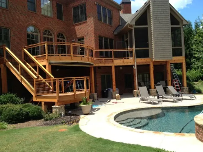 Swimming pool and raised spa beside a wood deck and stone patio