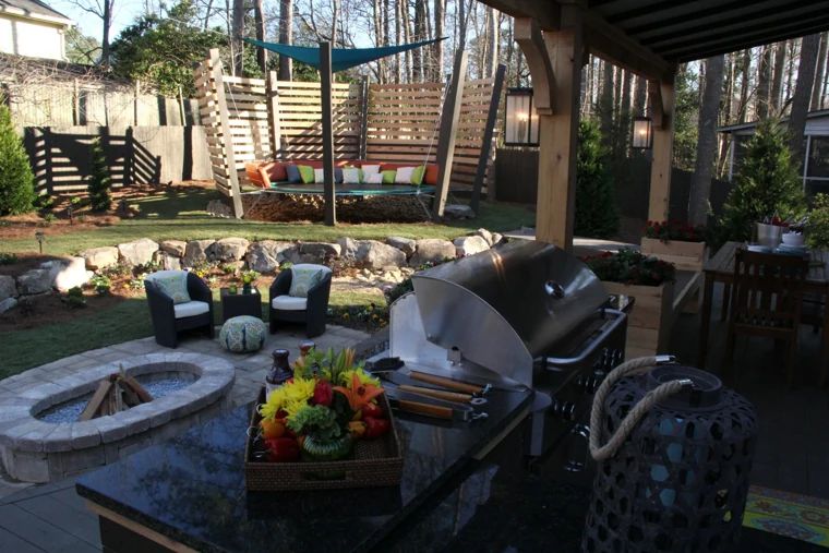 Outdoor grill and stone countertop overlooking a fire pit and garden seating