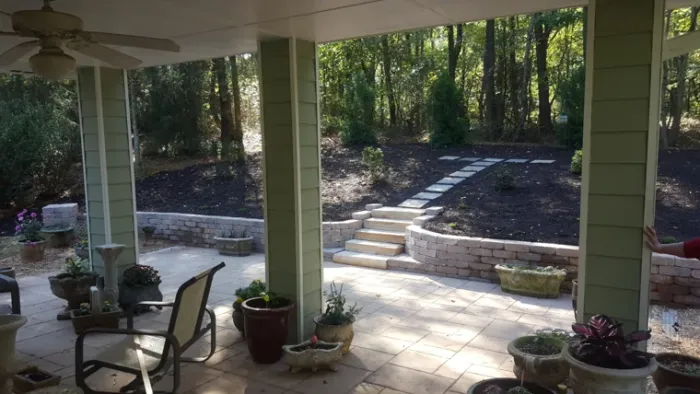 Stone retaining walls and broad steps around a shaded backyard patio