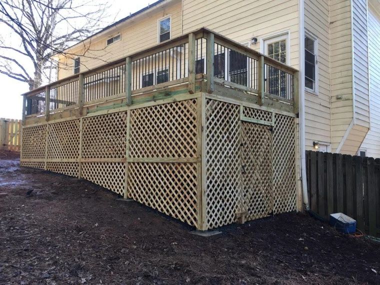Wood deck with dark railings, wide stairs, and lattice screening