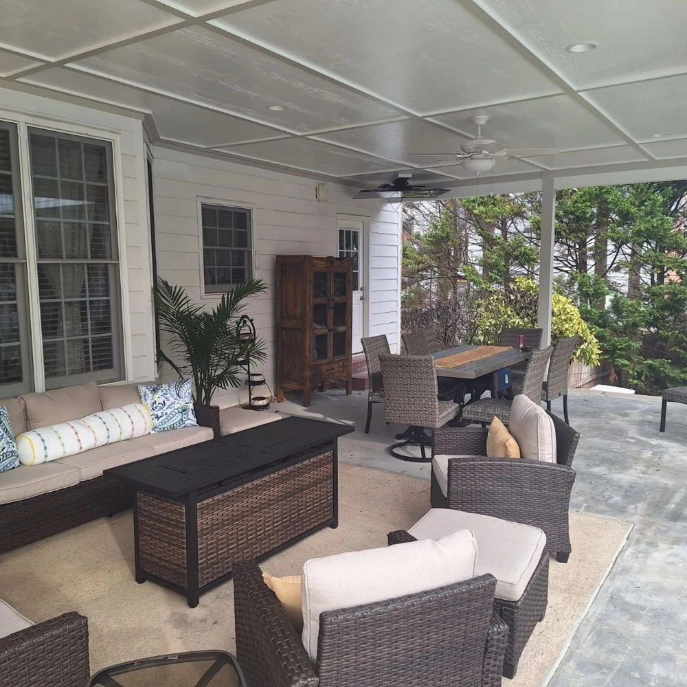 Covered patio furnished with woven lounge chairs and a dining table