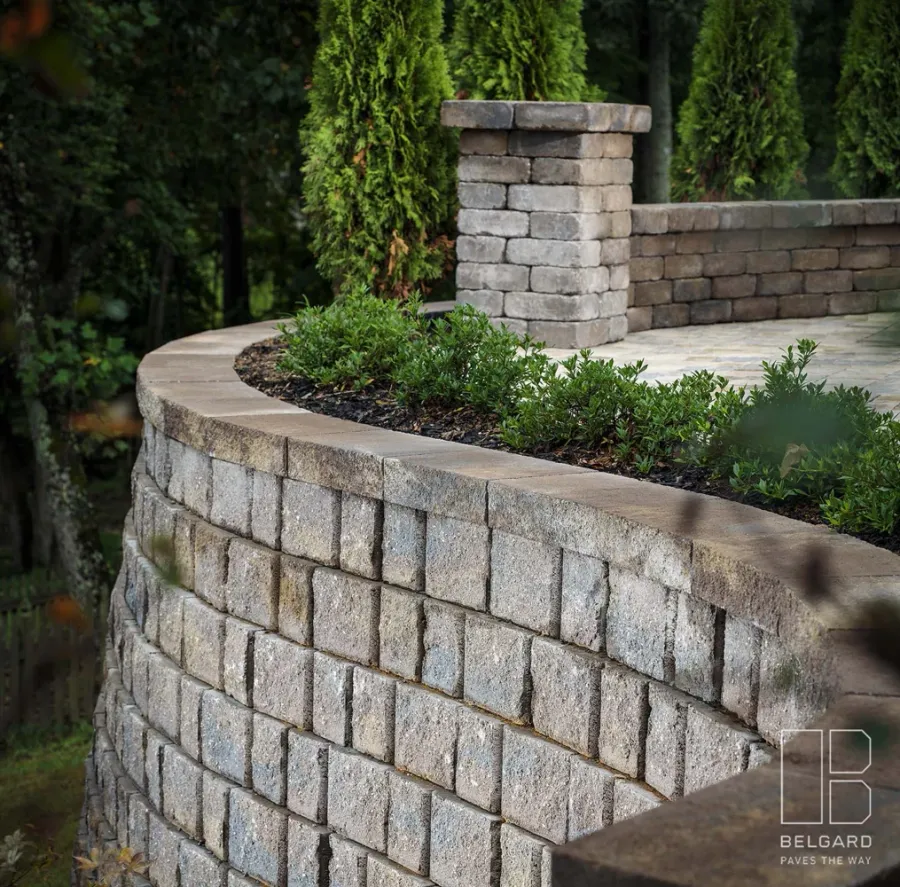 Curved stone garden wall with a planted bed and mature trees