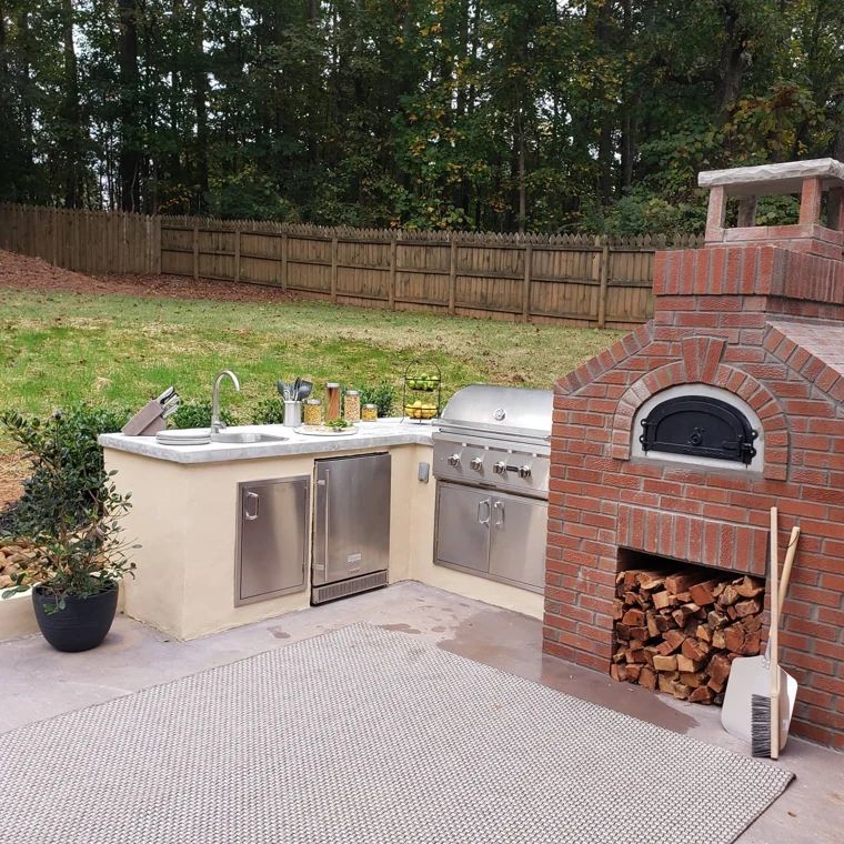 Outdoor kitchen with stainless steel appliances and a brick pizza oven