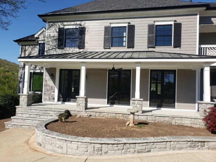Curving stone retaining wall and wide steps at the front of a home
