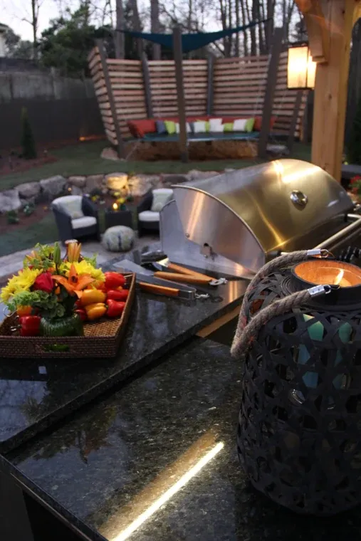 Stainless steel outdoor grill and stone countertop with fresh vegetables ready for cooking