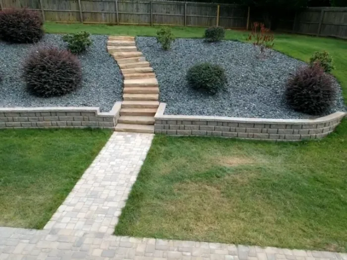 Two-tier retaining wall with central stone steps and planted beds