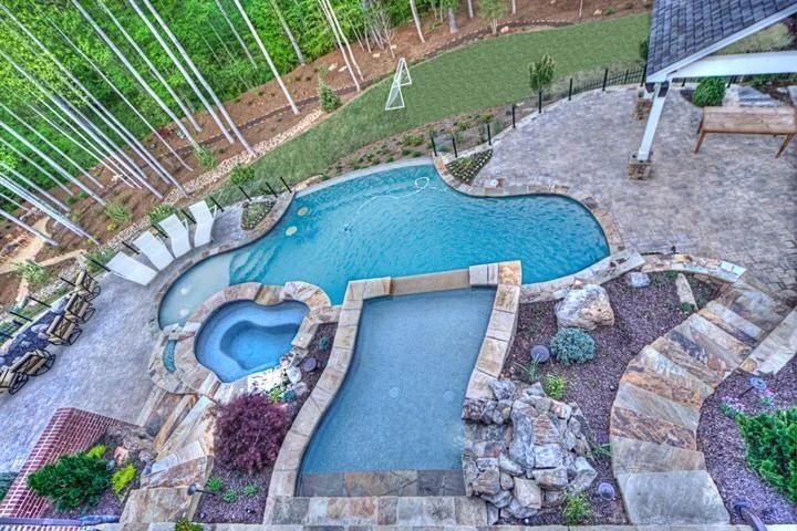 Freeform swimming pool, raised spa, and stone patio viewed from above