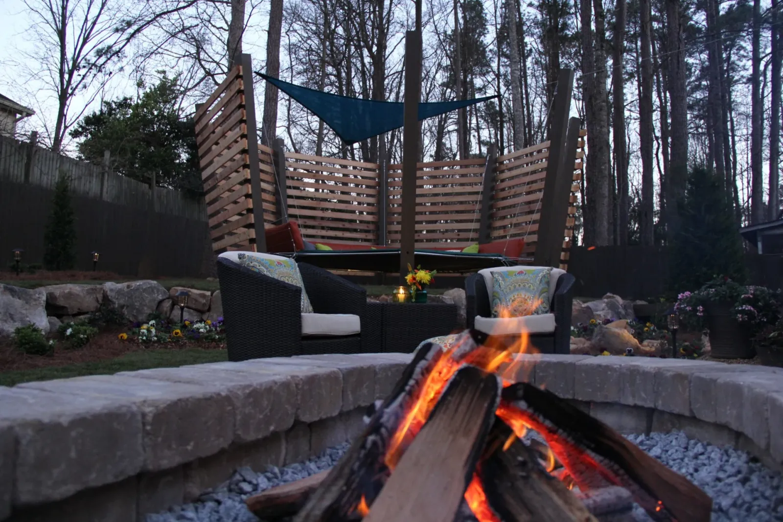 Glowing stone fire pit with lounge seating and a timber garden screen