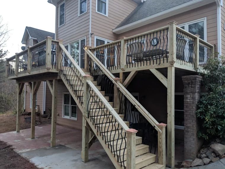 Wood deck with wide stairs and decorative dark metal balusters