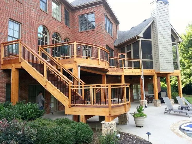 Two-level wood deck with black balusters and an adjoining patio