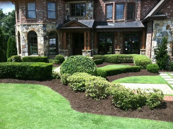 Formal front landscape with curved planting beds and a green lawn