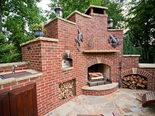 Custom brick outdoor fireplace beside an outdoor kitchen