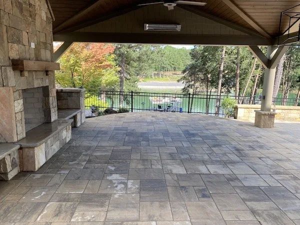 Paver patio beneath a timber pavilion with stone columns