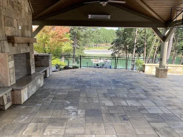 Paver patio beneath a timber pavilion with stone columns