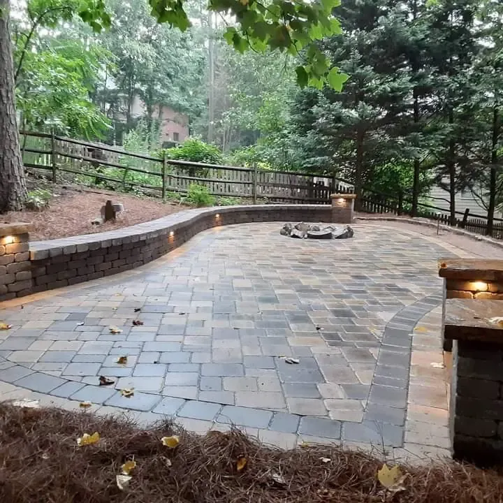 Curving paver patio with stone seating walls in a wooded yard