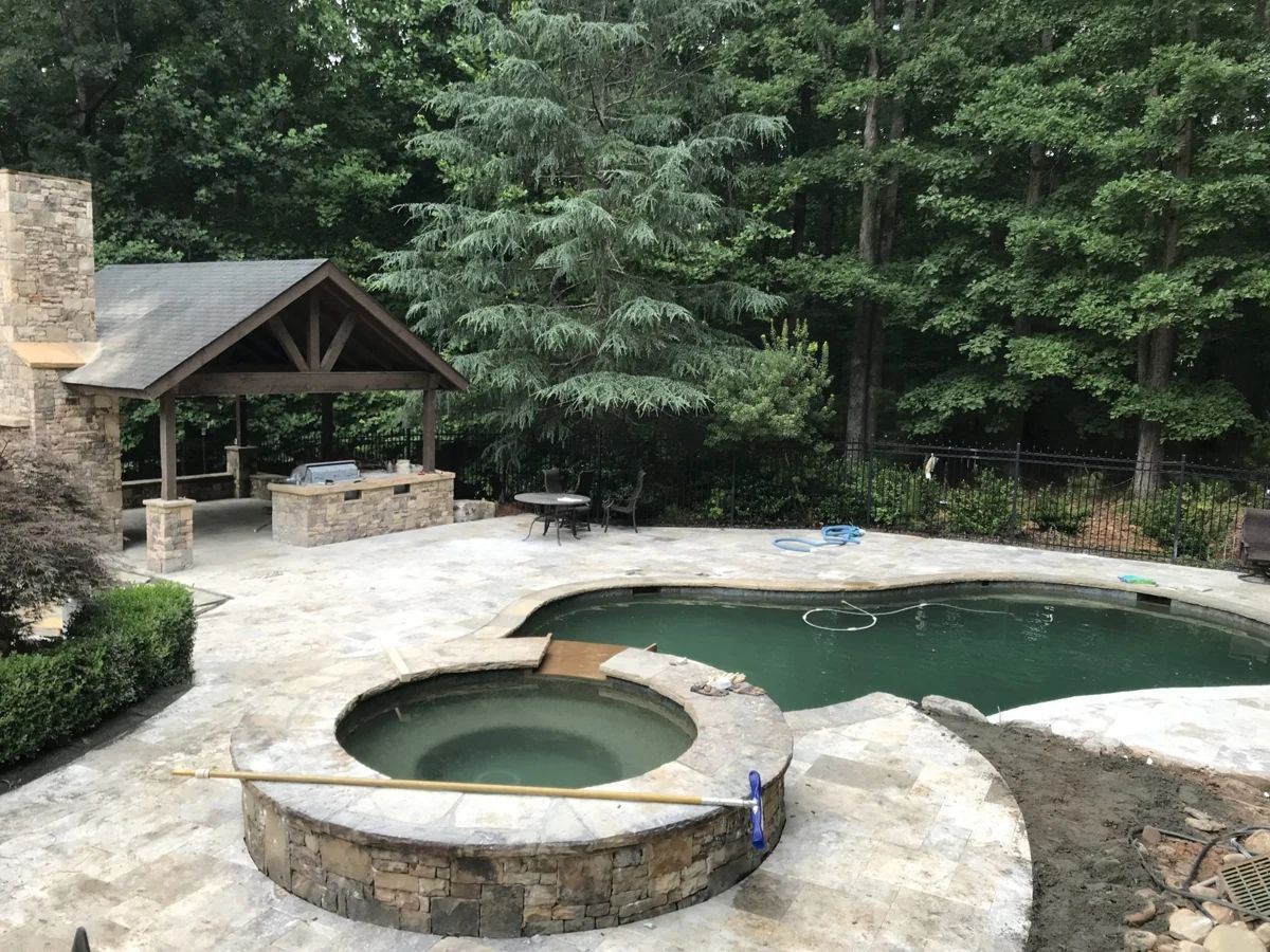 Pool and spa beside a woodland pavilion, tiered on a sloped lot