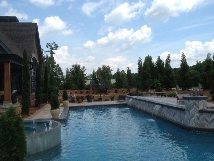 Custom pool with raised stone walls and spillway water features