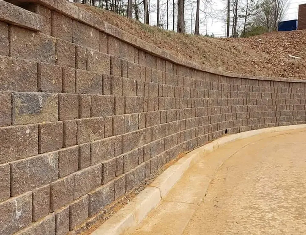 Curved segmental block retaining wall beside a paved area