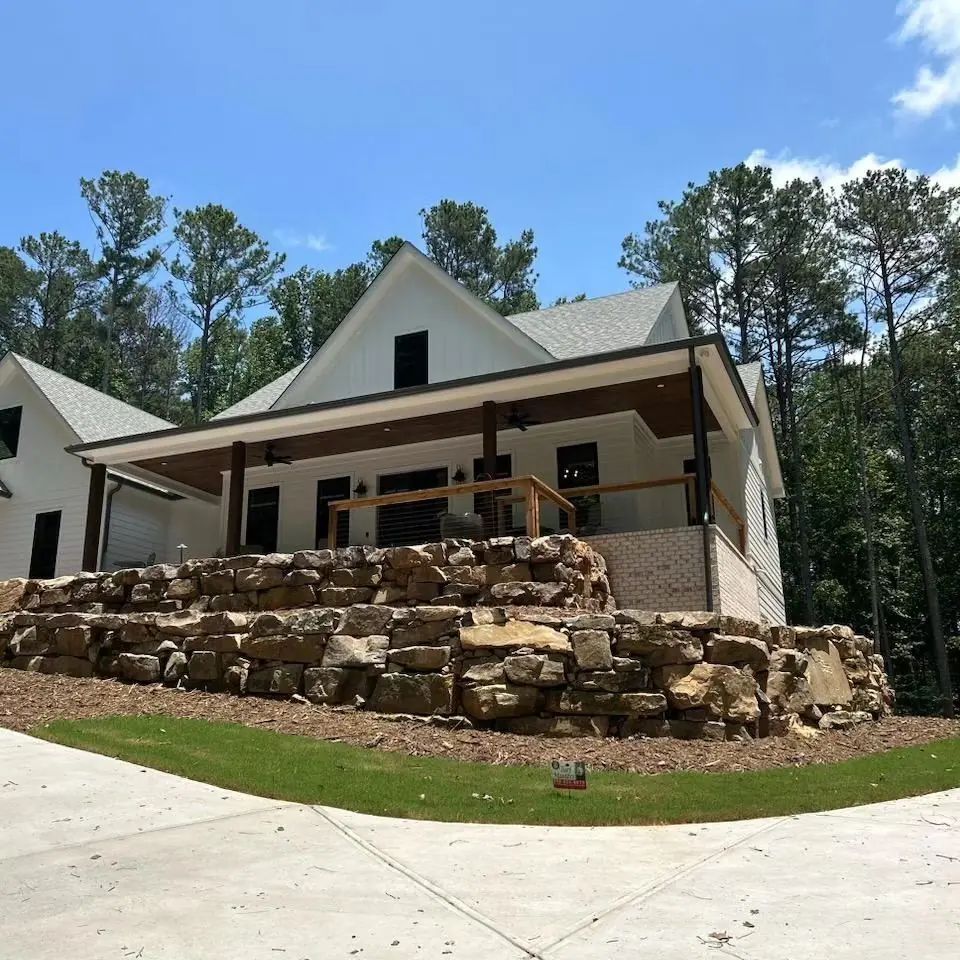 Natural boulder retaining wall across the front of a home