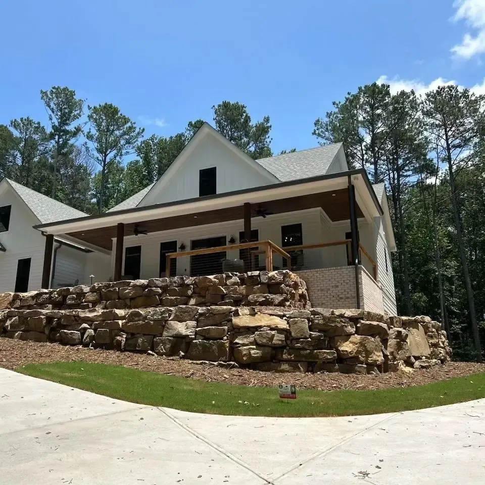 Natural boulder retaining wall across the front of a home