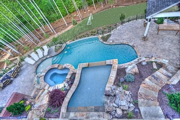Custom backyard pool and spa with stone patios and landscaped terraces