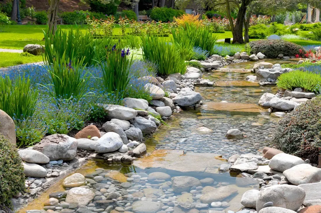 Flowing water feature lined with stone and lush planting