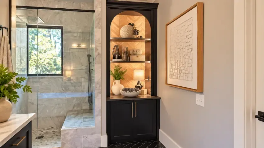 Dark arched cabinet with lit wood shelving beside a shower