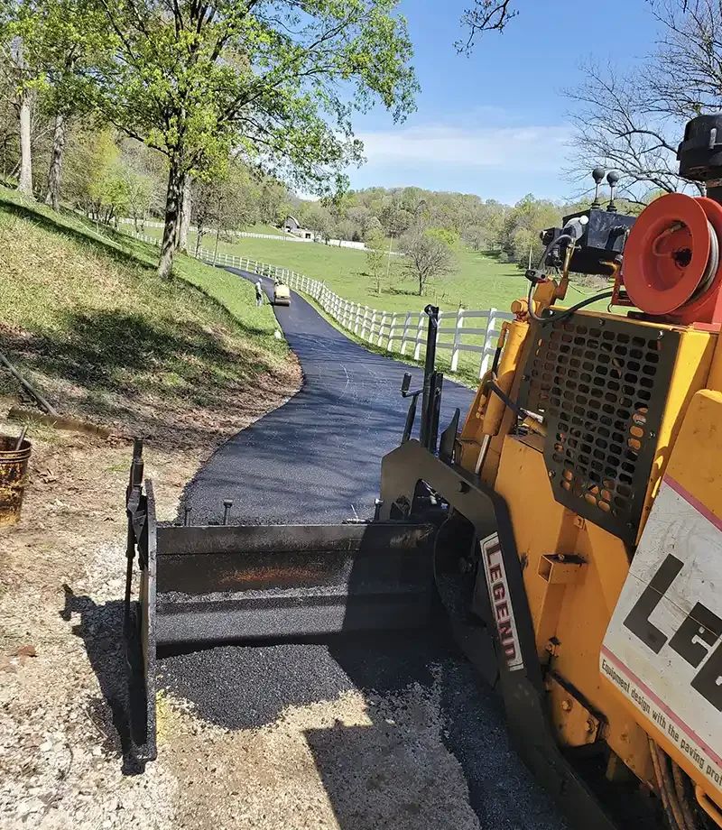Asphalt paving equipment finishing a residential driveway